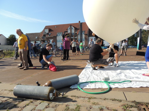Der teilweise gefüllte Ballon über einer weißen Plane, Helfer und Gasflaschen auf einem Platz in Schönebeck